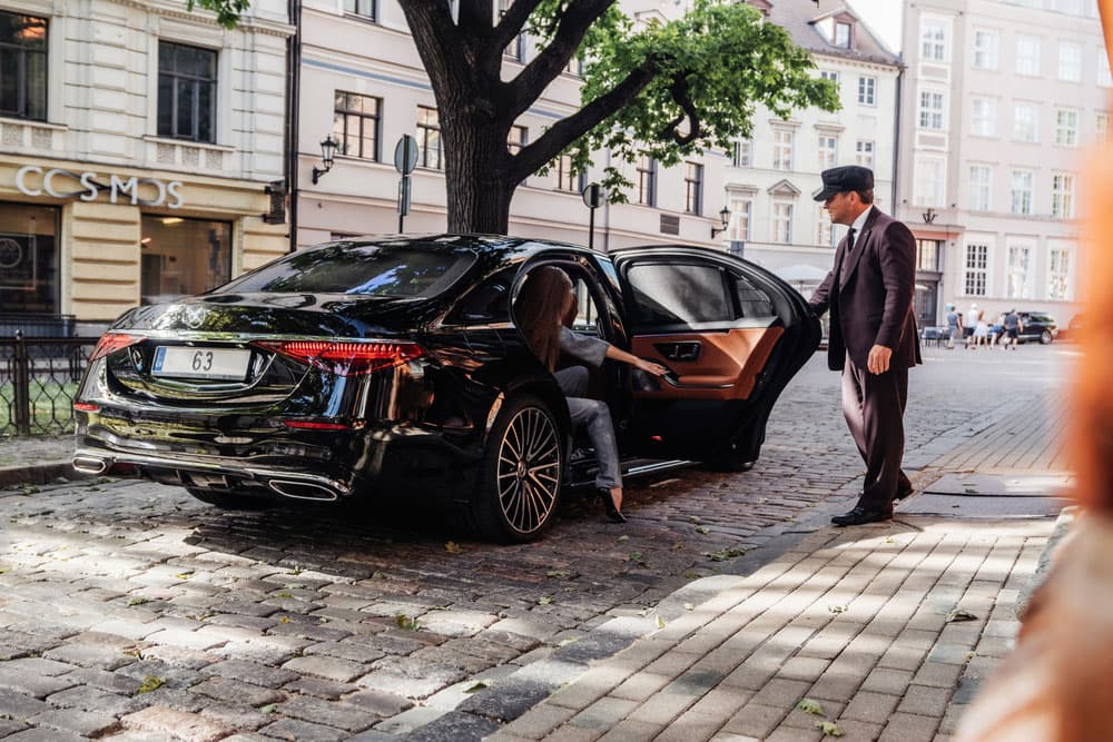 Bell Travels professional chauffeur next to a luxury sedan