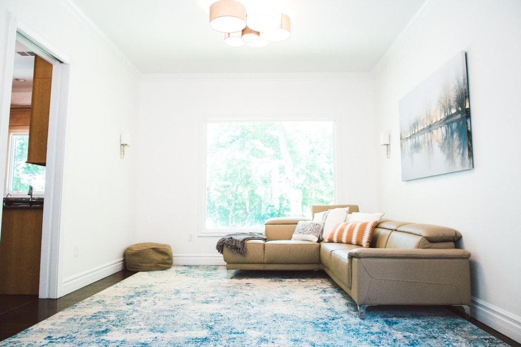 Bright living room with leather sectional and blue area rug